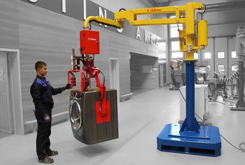 Dalmec manipulator with custom gripping tool handling a washing machine in an electromechanical appliance manufacturing facility, operated by a single worker