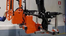 Dalmec manipulator with custom mechanical gripping tool handling a heavy automotive mechanical component on a production line