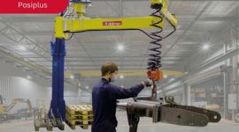 Cable-suspended industrial manipulator (Posiplus 200 kg) handling a heavy mechanical component for safe, precise, and ergonomic material handling in a manufacturing facility