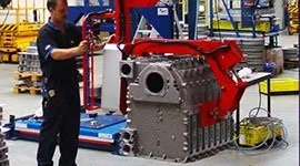 Technician inspecting a Dalmec manipulator unit used for heavy casting piece handling in a foundry.