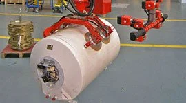 Dalmec manipulator with specialised gripper handling a large copper strap roll in a manufacturing facility