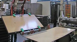 Dalmec manipulator with vacuum gripping tool lifting a timber door on a manufacturing line.