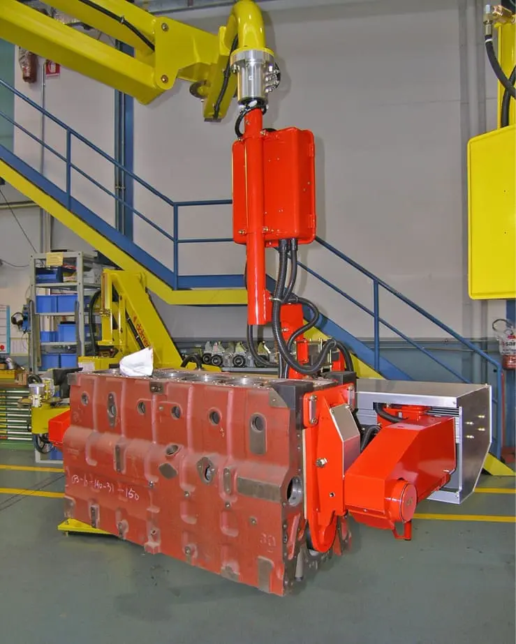 Dalmec manipulator with rotating gripping tool handling a heavy engine cylinder block on an automotive production line.