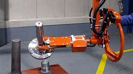 Dalmec orange manipulator arm handling a large gear component in a mechanical manufacturing facility