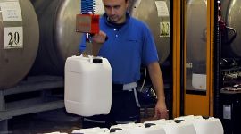 Dalmec vacuum manipulator lifting a plastic jerry can for safe, ergonomic handling in a pharmaceutical manufacturing facility.