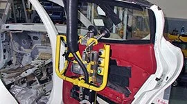 Dalmec manipulator with custom gripping tool handling a car door panel during automotive body assembly on the production line
