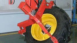 Dalmec manipulator with custom gripping tool handling a large tractor tyre and wheel assembly in an agricultural vehicle manufacturing facility