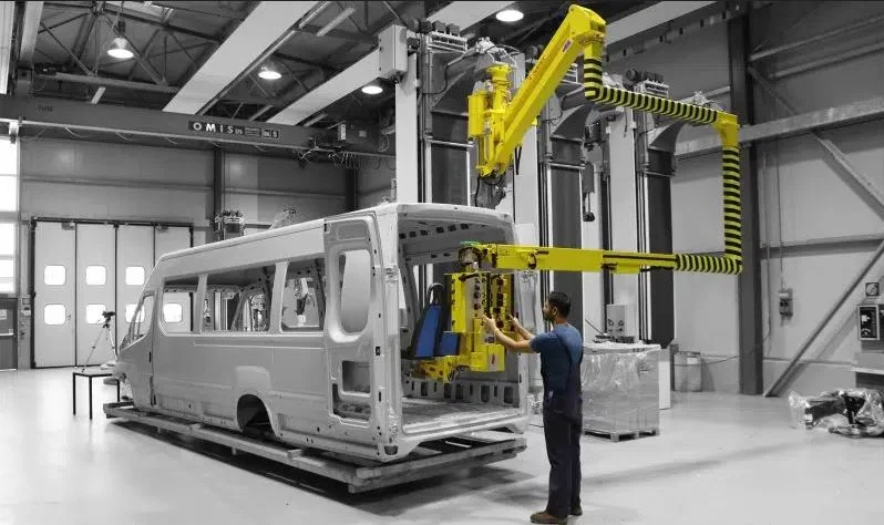 Dalmec manipulator with custom gripping frame handling a commercial vehicle body panel during automotive assembly, operated by a single worker