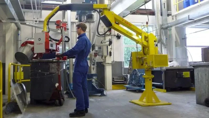 Dalmec manipulator handling a metal drum in a chemical processing facility, allowing a single worker to move heavy containers safely and ergonomically