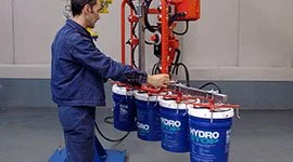 Dalmec manipulator with multi-hook gripping tool simultaneously lifting multiple chemical pails in an industrial facility