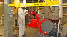 : Dalmec 150kg manipulator with drum-tilting gripper rotating a steel drum in a chemical processing warehouse