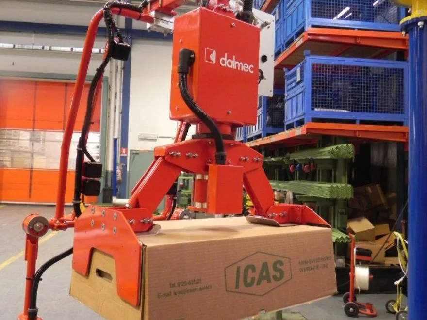 Close-up of Dalmec custom mechanical gripper tool securely gripping a large cardboard box in an industrial warehouse