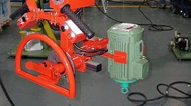 Dalmec manipulator with custom cradle gripping tool handling a heavy electric motor in an electromechanical manufacturing facility