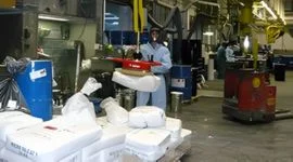 Dalmec manipulator handling ingredient bags in a food and agriculture processing facility, with workers managing bulk materials safely