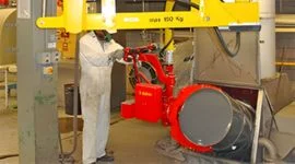 Dalmec 150kg manipulator with drum-tilting gripper rotating a steel drum in a food and agriculture processing facility, operated by a worker in PPE