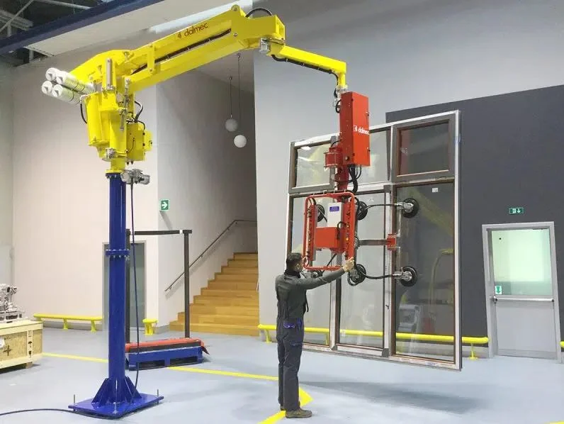 Dalmec manipulator with vacuum suction cup frame handling a large framed glass panel in a building construction facility, operated by a single worker