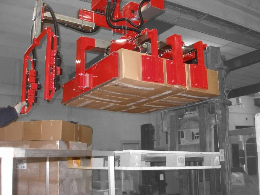 Dalmec overhead manipulator with large mechanical clamping frame lifting a full layer of cardboard boxes for palletising in a warehouse