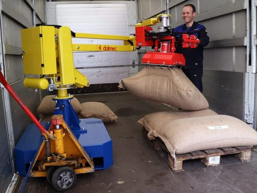 Dalmec mobile manipulator on a wheeled trolley base with custom gripper handling heavy hessian sacks during truck loading and unloading operations