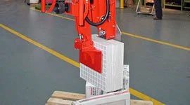 Dalmec manipulator with vacuum gripping tool lifting a stack of large paving tiles on a pallet in a building products warehouse