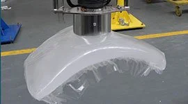 Dalmec manipulator with large vacuum suction cup gripping tool handling a moulded rubber or plastic component in a chemical manufacturing facility