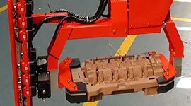 Dalmec manipulator with comb-style gripping tool handling microcasting pieces in a foundry.