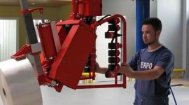 Dalmec pneumatic manipulator lifting and rotating a pharmaceutical packaging paper roll for safe, ergonomic material handling