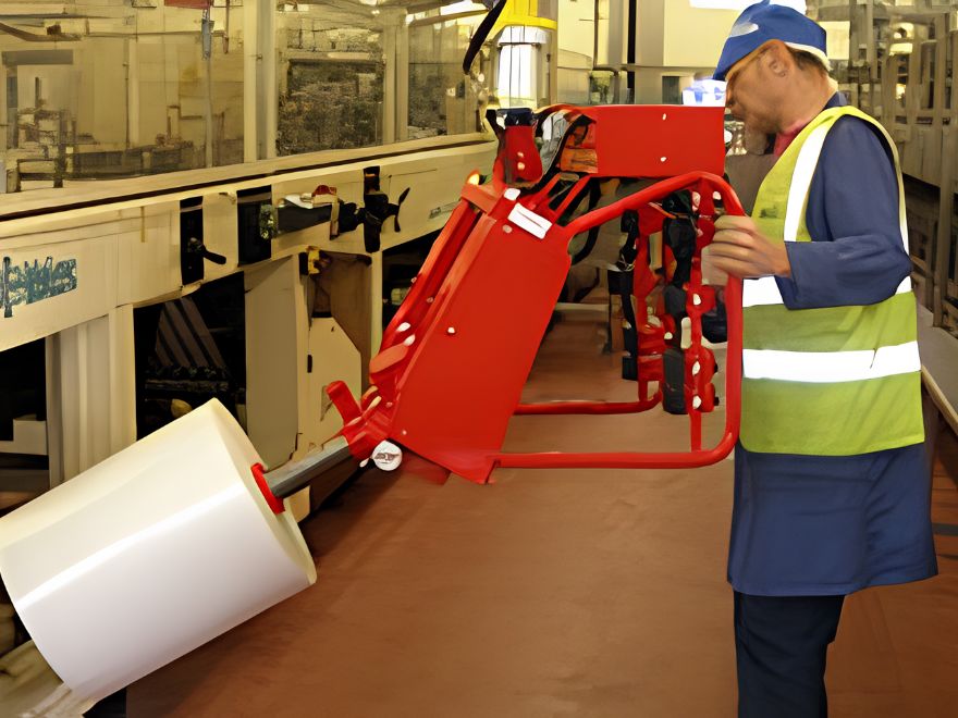 Dalmec pneumatic manipulator with a vacuum gripper lifting and positioning a paper roll in a paper and printing production facility.
