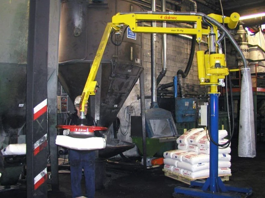 Dalmec Partner manipulator with vacuum gripping tool lifting and emptying a bag into an industrial hopper in a chemical processing facility