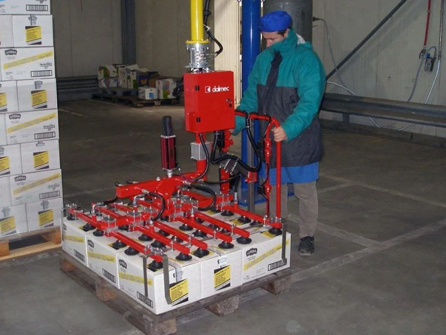Dalmec pneumatic manipulator with large multi-suction cup frame lifting an entire layer of carton boxes from a pallet in a cold storage warehouse