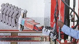 Dalmec rigid-arm manipulator with multi-finger gripping tool handling precision casting pieces in a foundry.