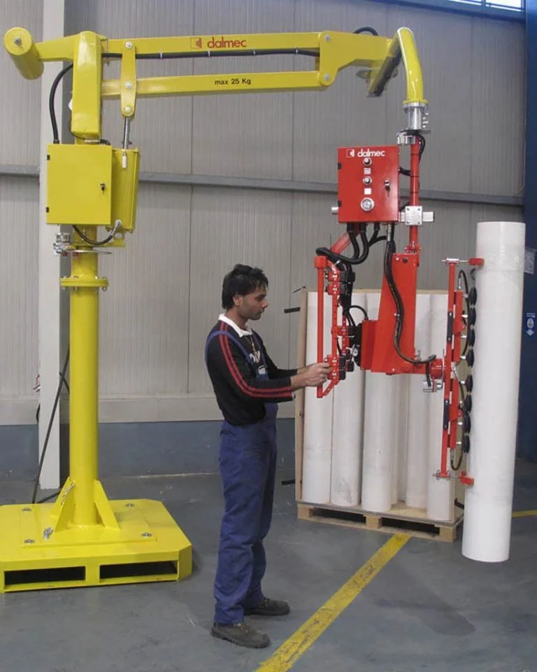 Dalmec rigid-arm manipulator with multi-clamp gripping tool, rated to 25 kg, lifting and rotating paper reels as a worker guides positioning.