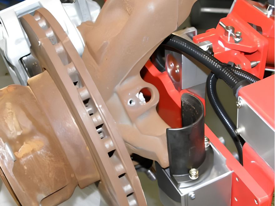 Close-up of a custom industrial manipulator gripper securely holding a heavy automotive wheel hub and brake disc assembly for ergonomic lifting and precision handling.