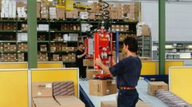 Vacuum box lifting manipulator handling cardboard boxes on a conveyor system for efficient warehouse material handling.