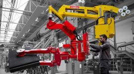 Industrial vacuum composite panel lifting manipulator with suction gripper handling a large composite panel for safe, precise, and ergonomic material handling in a manufacturing facility