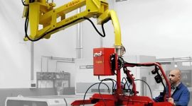 Industrial vacuum glass sheet lifting manipulator with suction cups handling a large glass panel for safe, precise, and ergonomic material handling in a manufacturing facility