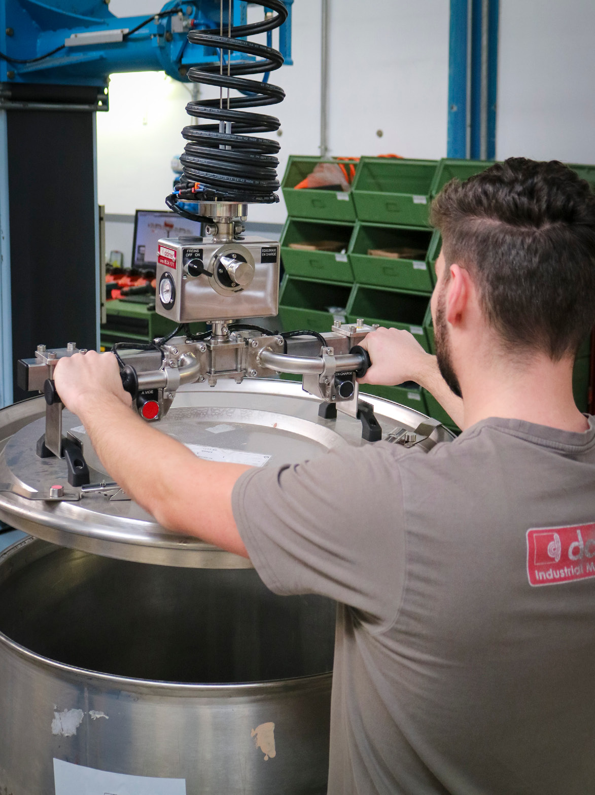 Close-up of a Dalmec vacuum gripper securely handling a stainless steel drum cover.