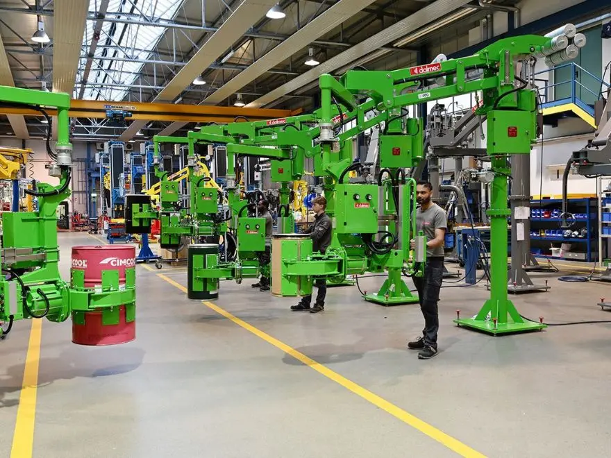 Multiple Dalmec pneumatic drum handling manipulators lifting steel and fibre drums, operators guiding the loads