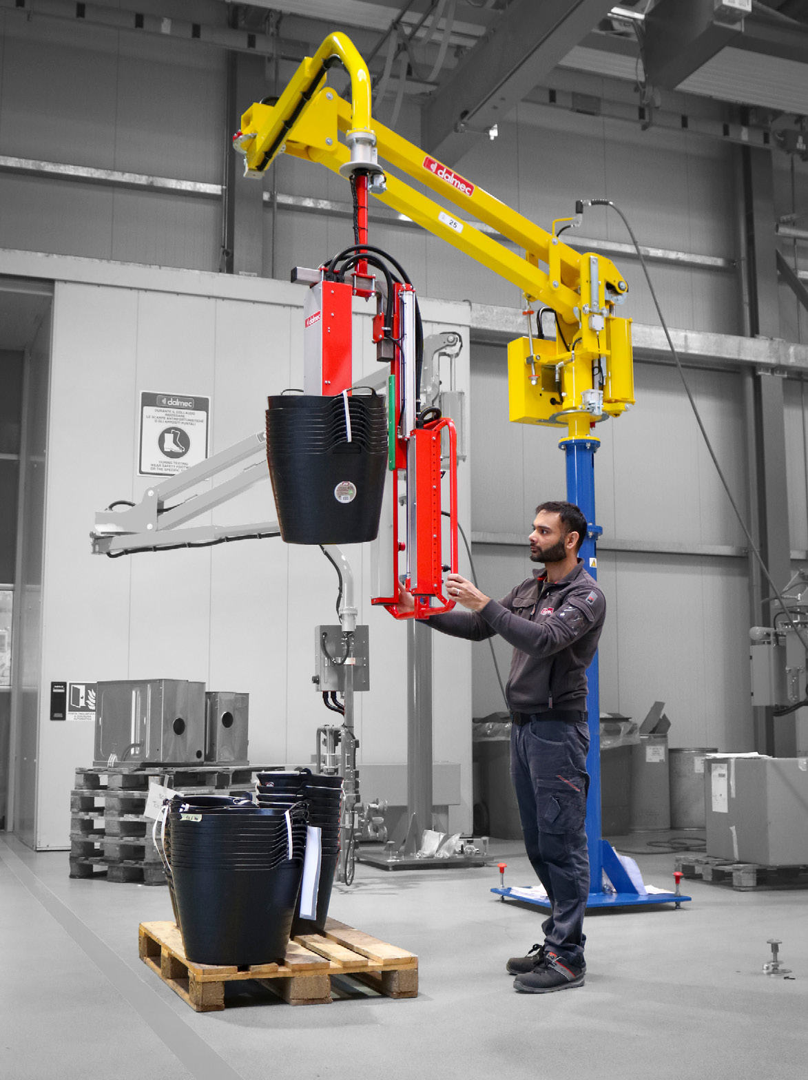 Dalmec industrial manipulator safely lifting stacked plastic containers for ergonomic material handling.