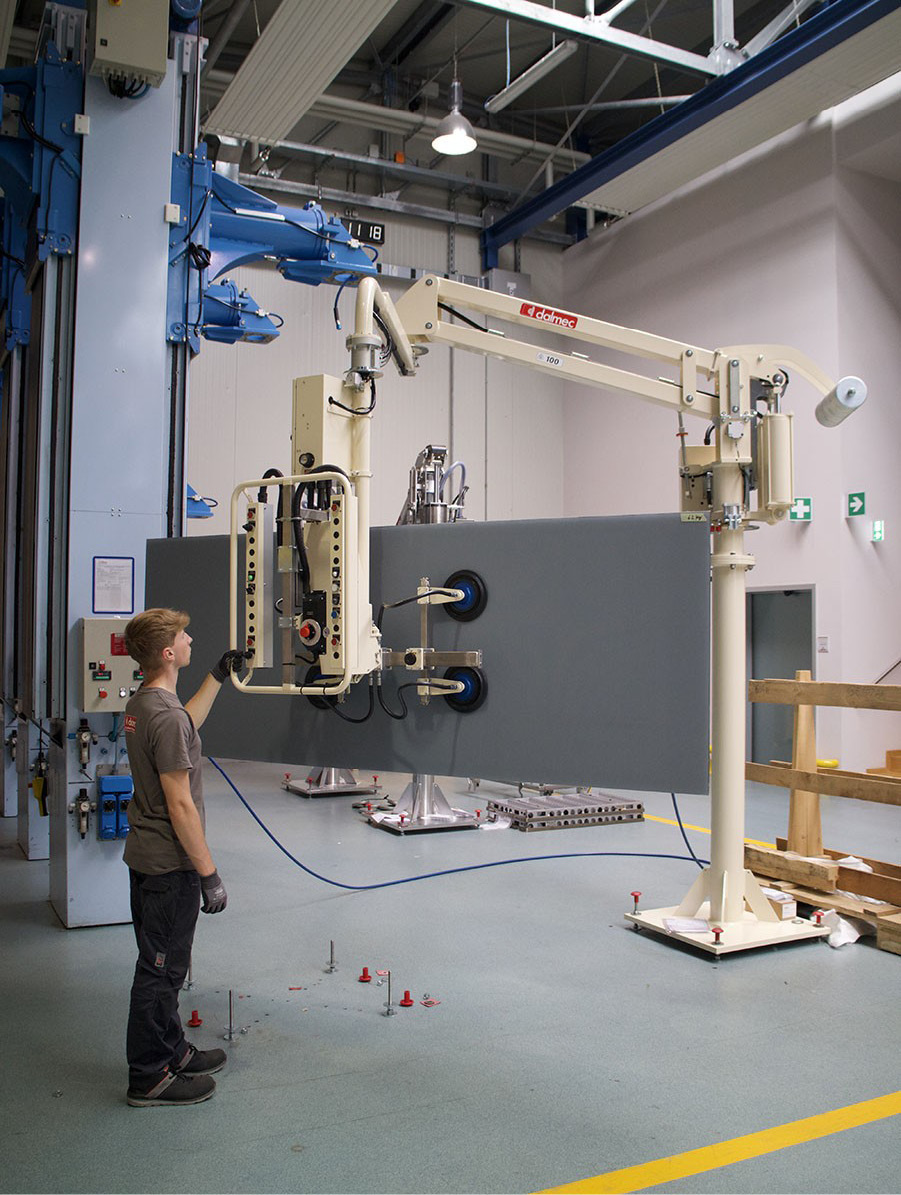 Dalmec vacuum lifting device transporting a heavy steel plate across a fabrication workstation.