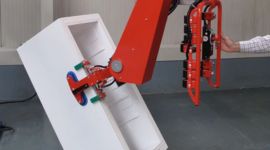 Dalmec manipulator lifting plastic containers for safe, ergonomic handling in plastics manufacturing operations.