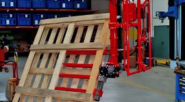 Dalmec pneumatic manipulator lifting a large timber panel for safe, ergonomic handling in a wood processing facility.